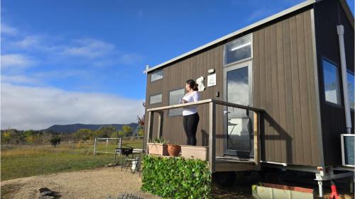 a woman standing on the porch of a tiny house at Little Lady Cabin by Tiny Away in Rylstone