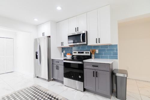 a kitchen with white cabinets and a stainless steel refrigerator at West Palm Beach Elegant 5BR with Hot Tub and Fire Pit Near Beach in West Palm Beach
