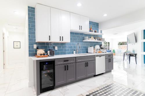 a kitchen with white cabinets and blue tiles at West Palm Beach Elegant 5BR with Hot Tub and Fire Pit Near Beach in West Palm Beach