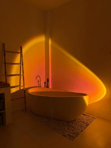 a bathroom with a bath tub with lights on the wall at Blue Origin Bali in Munggu