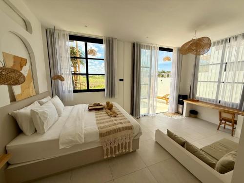Un dormitorio con una cama grande y grandes ventanales. en Blue Origin Bali, en Munggu
