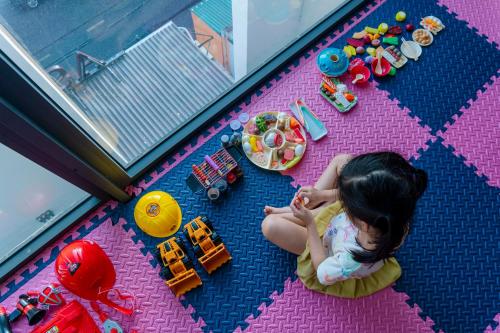 a little girl sitting on the floor playing with toys at Astica Hotel Nha trang in Nha Trang
