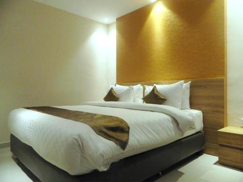 a bedroom with a large bed with a wooden headboard at Wing Hotel Kualanamu Airport in Medan