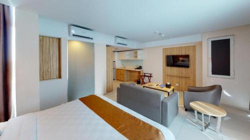 a bedroom with a bed and a desk and chairs at Wing Hotel Kualanamu Airport in Medan