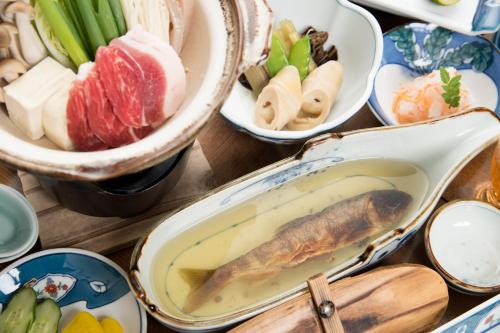 a table with bowls of food with a fish in it at Bijintei in Tanabe