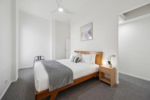 Un dormitorio blanco con una cama y una mesita de noche. en The Break on Diggers - Popular Location, walk to Beach, en Coffs Harbour