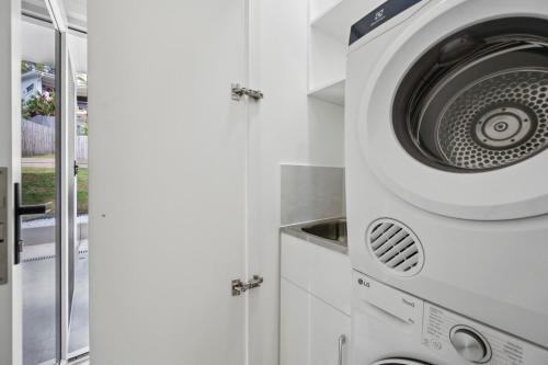 a washer and dryer in a white kitchen at The Break on Diggers - Popular Location, walk to Beach in Coffs Harbour