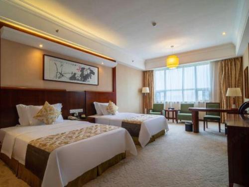 a hotel room with two beds and a desk at Xiangtan Xintian International Hotel in Xiangtan