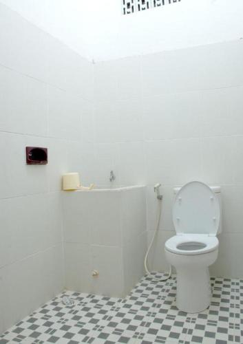 a bathroom with a white toilet and a black and white tile floor at Hotel Wijaya Magelang in Magelang