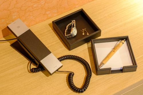 a phone and a box with a pen and a watch at Tosei Hotel Cocone Kamata in Tokyo