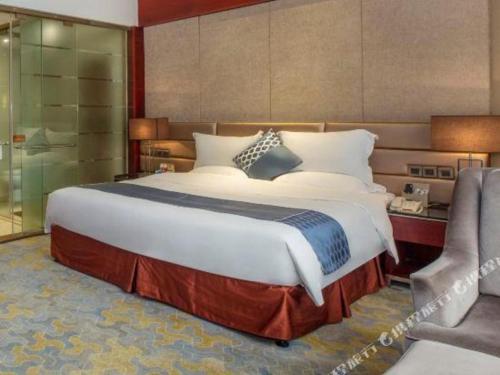 a bedroom with a large bed and a chair at Quanzhou Jinjiang Hollyston Hotel in Quanzhou