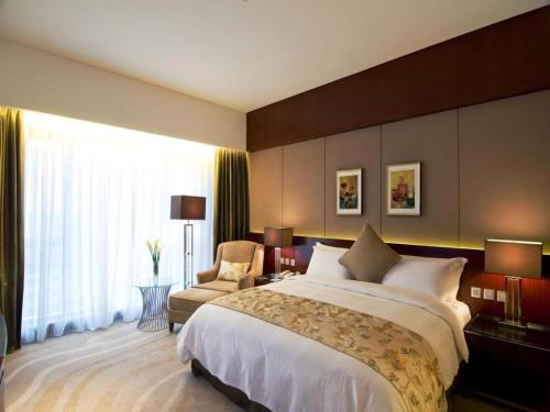 a large bedroom with a large bed and a chair at Quanzhou Jinjiang Hollyston Hotel in Quanzhou