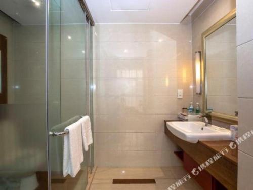 a bathroom with a glass shower and a sink at Quanzhou Jinjiang Hollyston Hotel in Quanzhou