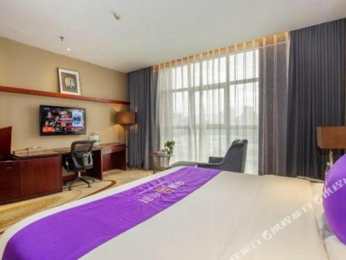 a hotel room with a large bed and a desk at Quanzhou Jinjiang Hollyston Hotel in Quanzhou