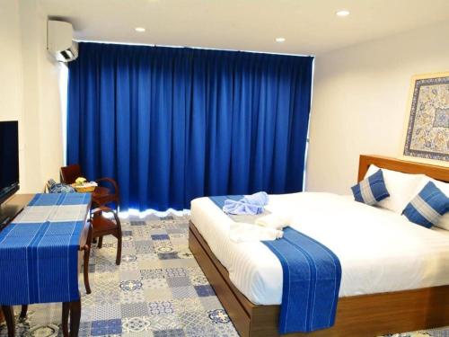 a bedroom with two beds and a blue curtain at The Indigo House Phrae in Phrae
