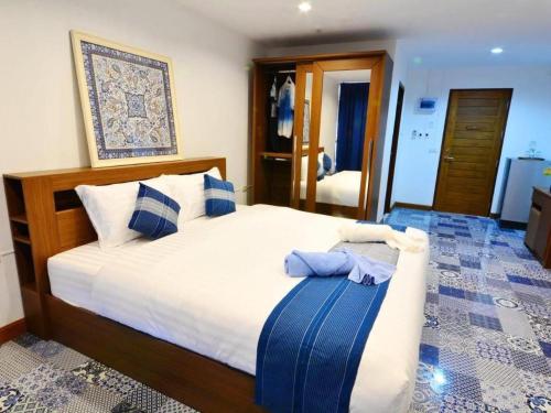 a bedroom with a large bed with blue and white pillows at The Indigo House Phrae in Phrae