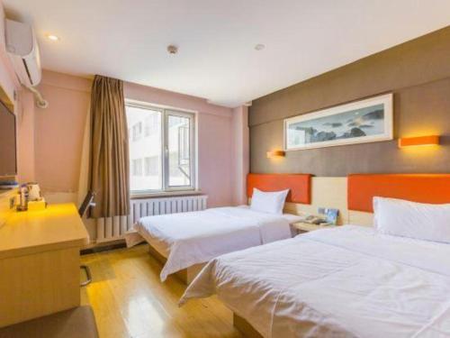 a hotel room with two beds and a desk at 7 Days Premium Hohhot Hailiang Square in Hohhot