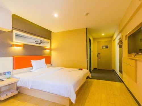 a bedroom with a large white bed and a television at 7 Days Premium Hohhot Hailiang Square in Hohhot