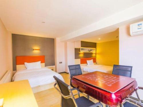 a hotel room with two beds and a table and chairs at 7 Days Premium Hohhot Hailiang Square in Hohhot