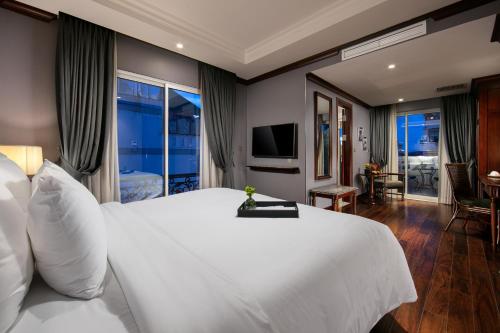 a bedroom with a large white bed and a television at La Sinfonía Majesty Hotel and Spa in Hanoi