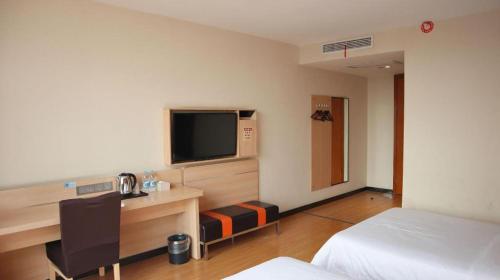 a hotel room with a bed and a desk with a television at 7Days Premium Yichang Railway Station East in Yichang