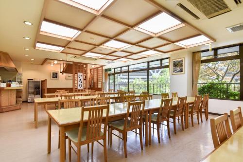a dining room with tables and chairs and windows at Bijintei in Tanabe