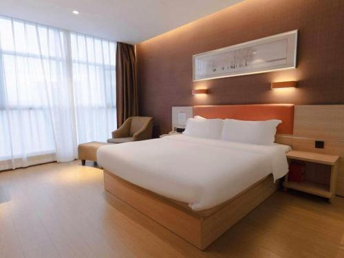 a hotel room with a large bed and a chair at 7Days Premium Yichang Railway Station East in Yichang