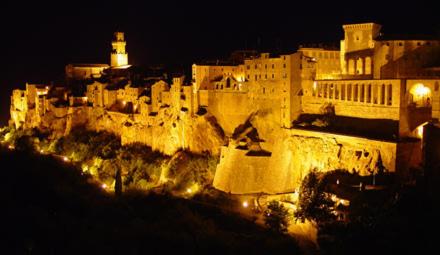 a city lit up at night with a castle at Le Camere Del Ceccottino in Pitigliano