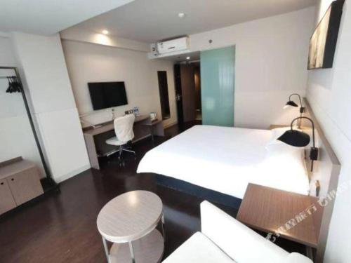 Una habitación de hotel con una cama blanca y una mesa y sillas. en Jinjiang Inn Select Xi'an Hongmiaopo East Daxing Road, en Xi'an