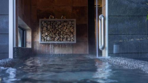 a swimming pool with water coming out of a building at Yufuin Luxury Villa -zakuro- in Yufuin