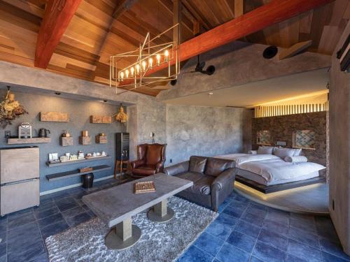 a bedroom with a bed and a couch and a table at Yufuin Luxury Villa -zakuro- in Yufuin