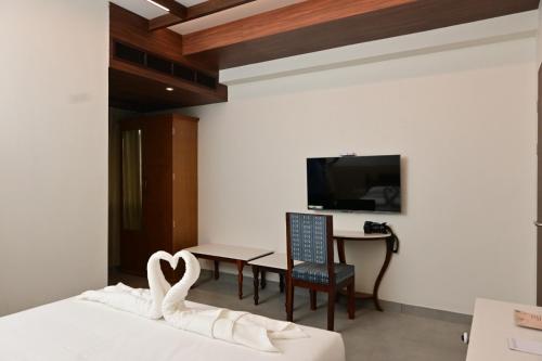 a bedroom with a bed and a table and a tv at Rathna Residency in Tiruppattūr