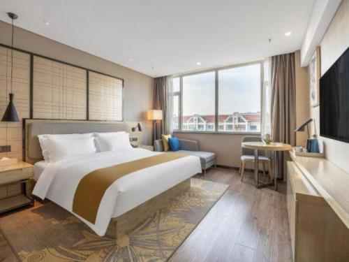 a hotel room with a large bed and a desk at Echarm Hotel Zibo Gaoqing Zhongcheng Inernational in Zibo