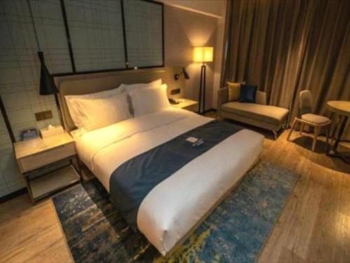 a large bedroom with a large bed and a chair at Echarm Hotel Zibo Gaoqing Zhongcheng Inernational in Zibo