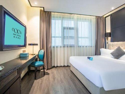 a hotel room with a bed and a desk and a television at Xana Hotelle Nanchang Tengwang Pavilion Wanshougong in Nanchang