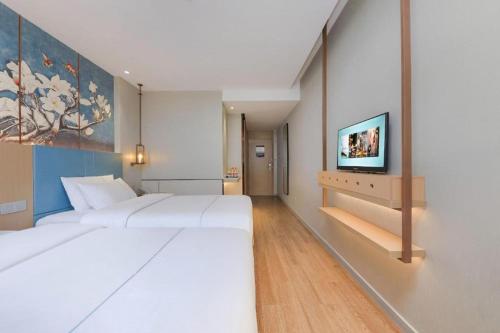 a bedroom with a large white bed and a tv at Magnotel Hotel Xiamen North Station Binhai in Xiamen