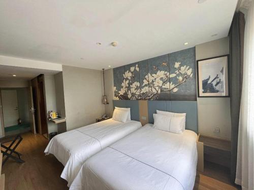 a hotel room with two beds and a painting on the wall at Magnotel Hotel Xiamen North Station Binhai in Xiamen