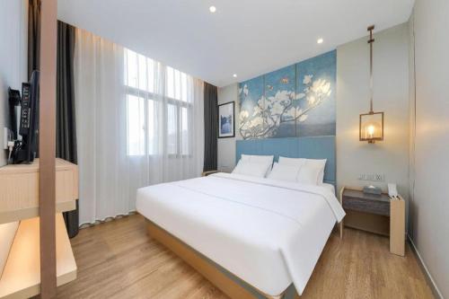 a large white bed in a hotel room at Magnotel Hotel Xiamen North Station Binhai in Xiamen