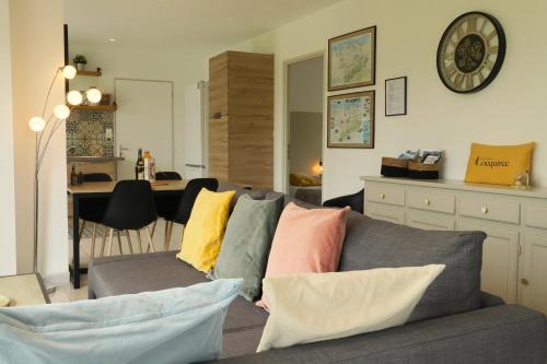 a living room with a gray couch with colorful pillows at maison de vacances locquirec in Locquirec