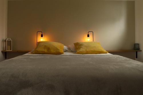 a large bed with two yellow pillows on it at maison de vacances locquirec in Locquirec
