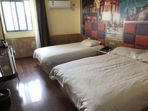 a hotel room with two beds and a painting on the wall at Ease Hotel Shanghai Chuanhuan Nan Road Chuansha Metro Station in Shanghai