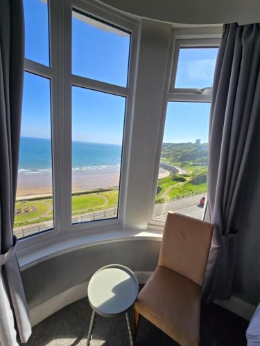 a room with two chairs and a window with the ocean at Boston Hotel in Scarborough