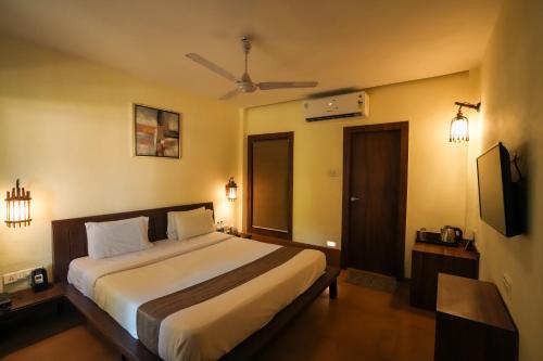 a bedroom with a large bed and a television at Adamo The Village in Matheran