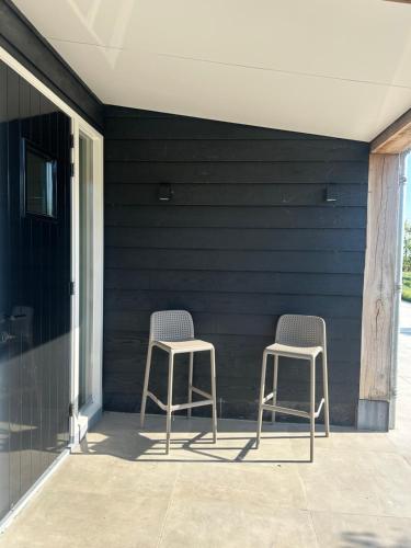 two chairs sitting on a porch next to a wall at Suite Ouddorp - 2 pers in Ouddorp