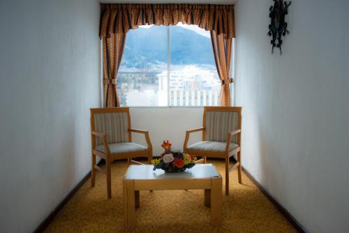 a room with two chairs and a table and a window at Hotel 6 De Diciembre in Quito