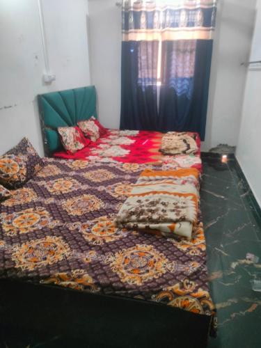 a bedroom with a bed with a quilt on it at Mathura vrindavan Gokul Dham in Mathura