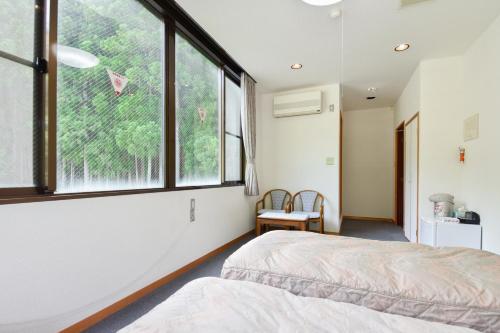 a bedroom with two beds and a large window at Bijintei in Tanabe