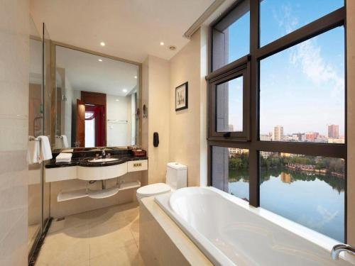 a bathroom with a tub and a large window at Vienna Hotel Henan Xinyang East Zone of Central Hospital in Pingqiao