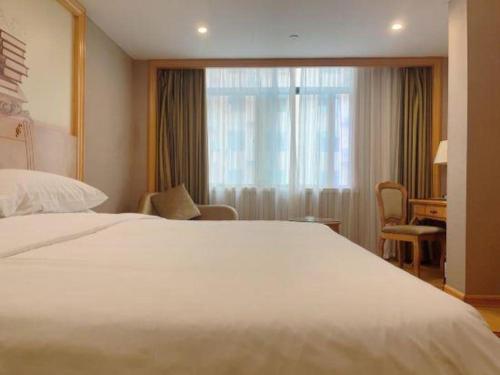 a hotel room with a large bed and a window at Vienna Hotel Guangxi Fangcheng in Fangcheng