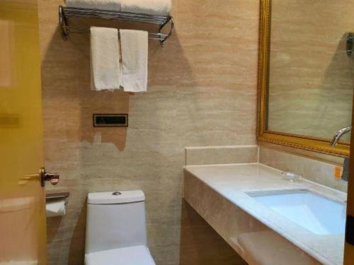 a bathroom with a toilet and a sink and a mirror at Vienna Hotel Guangxi Fangcheng in Fangcheng
